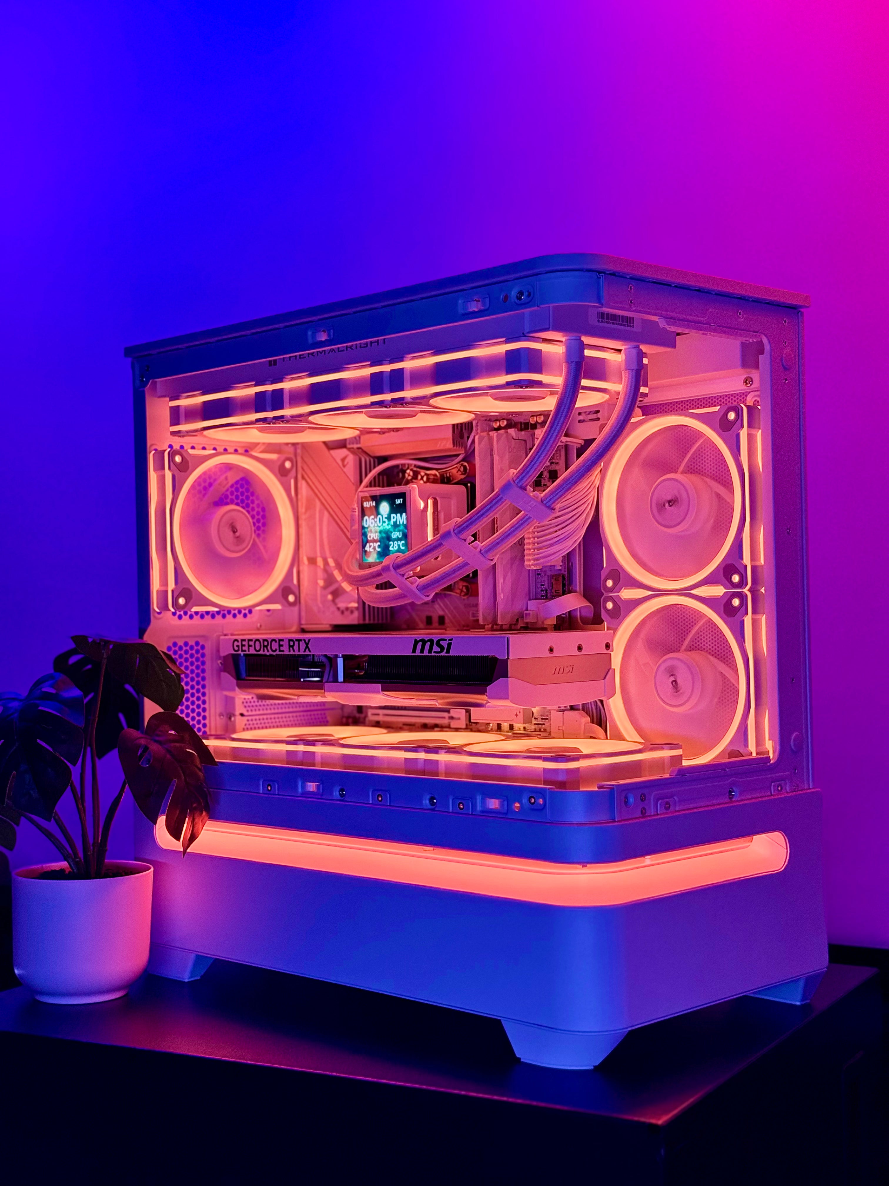 Computer case with visible components under purple lighting, potted plant on the side.