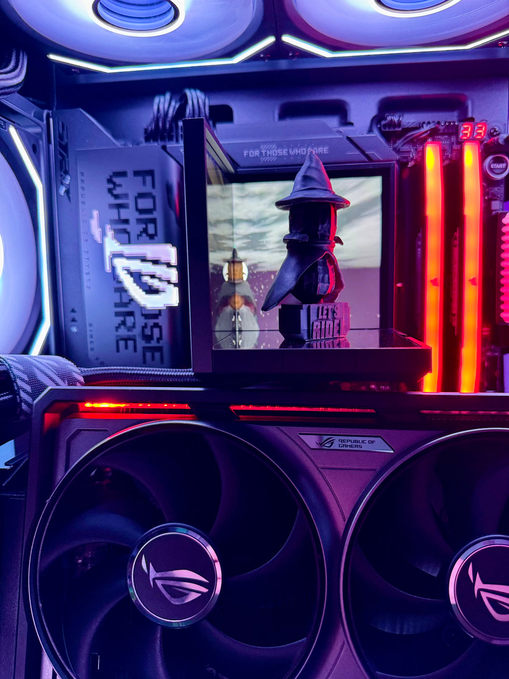 Close-up of a computer case with RGB lighting and a monitor displaying a character in a hat.