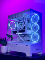 A white custom PC tower with a transparent side panel, illuminated by glowing blue LED fans and RGB lighting, set against a purple ambient background with a small potted plant on the left.