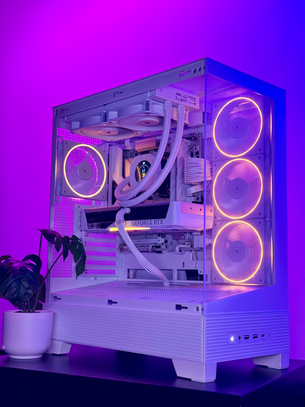 A white custom desktop PC tower with a transparent side panel, showcasing internal components and RGB cooling fans, set against a glowing purple background.