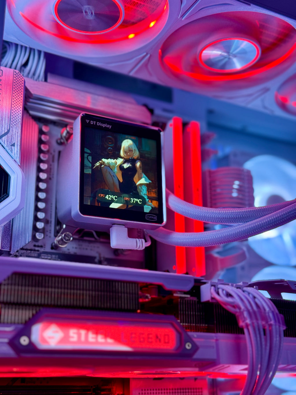 A close-up of a custom PC build with a liquid CPU cooler featuring a small digital temperature display screen, illuminated by red and purple LED lights. The AIO cooler has a translucent purple tube and a black radiator with a red 'STEEL LEGEND' logo on the front.