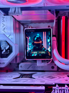 A desktop PC interior with RGB lighting in pink, purple, and red, featuring a small square in-circuit display screen mounted on the motherboard. The screen shows a futuristic helmeted character and temperature readings.