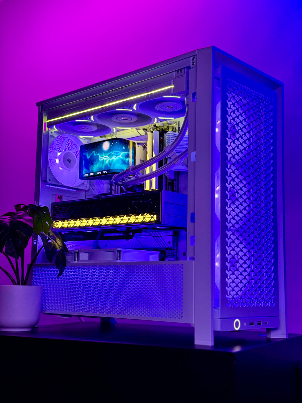 A custom white PC tower with a glass side panel, showcasing internal components illuminated by purple and blue LED lighting, set against a dark background with a small potted plant in the foreground.