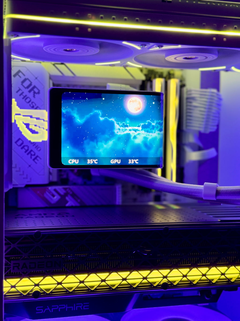 A close-up of a custom PC tower interior with a liquid CPU cooler, glowing yellow LED strip lighting, and a display screen showing blue and white graphics with CPU and GPU temperatures.