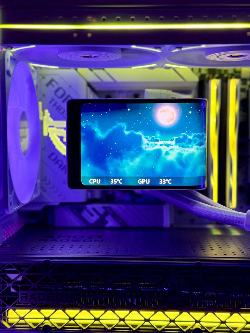 A close-up of a custom liquid CPU cooler with a transparent side panel, illuminated by purple and yellow LED lights. The cooler features a black radiator with a large purple fan, a tube carrying the coolant, and a digital temperature display screen showing CPU and GPU temperatures.