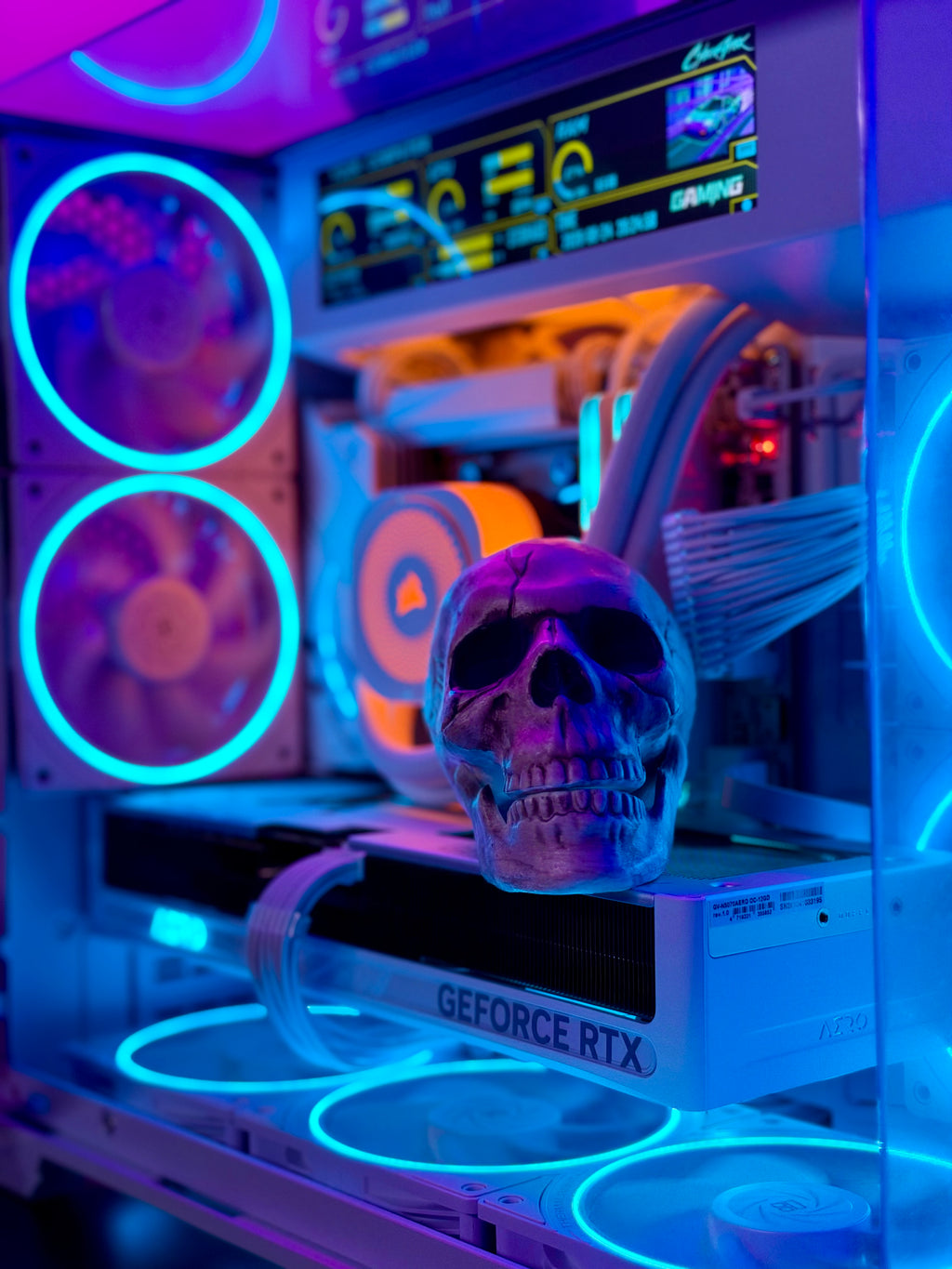 A custom PC build with a clear side panel showing internal components illuminated by blue and orange LED lights, featuring a decorative skull figurine in the foreground.