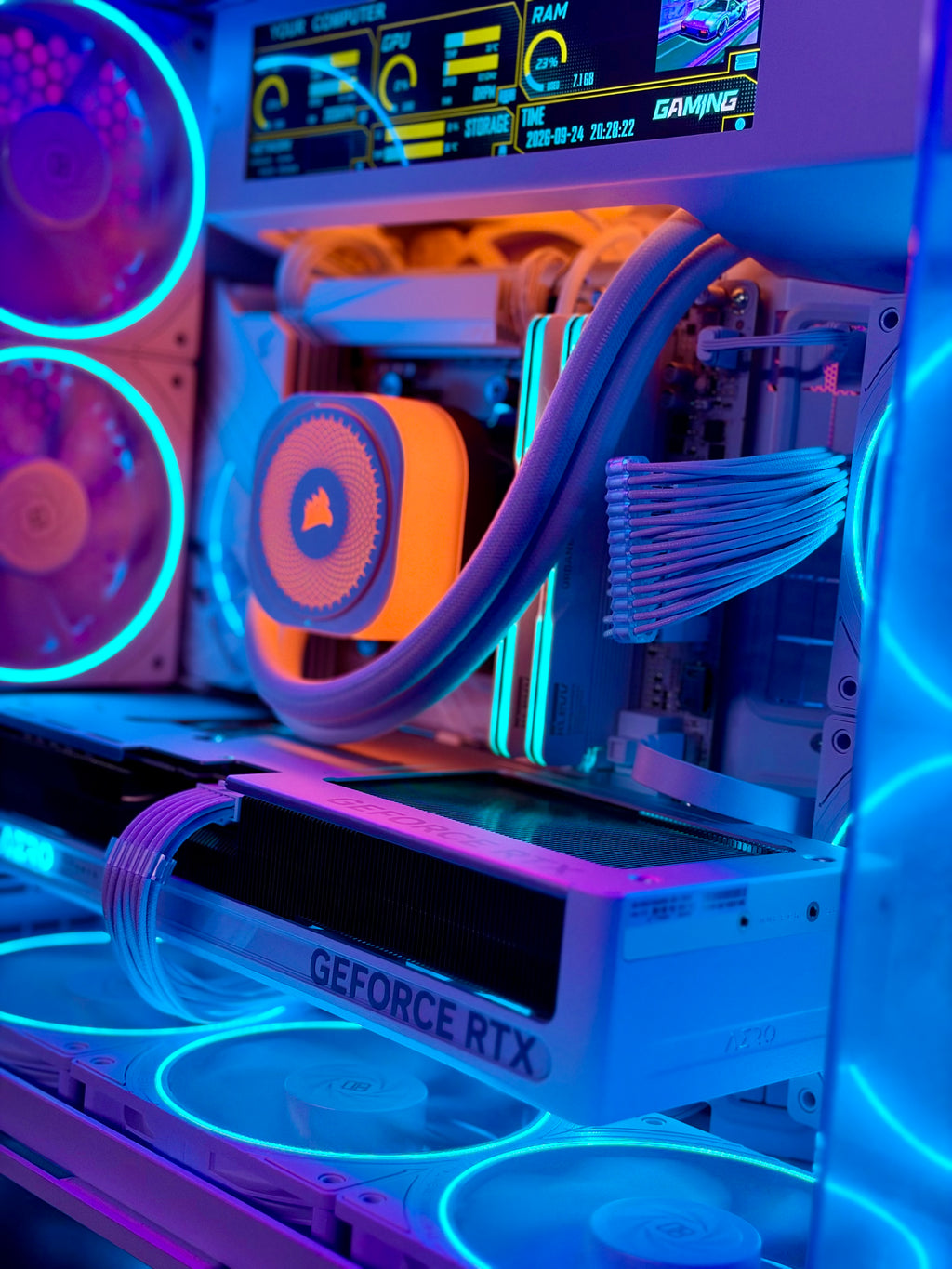 A close-up of a custom PC build with neon RGB lighting, featuring a white GeForce RTX graphics card, a liquid CPU cooler with an orange accent, and multiple fans glowing in blue and purple.
