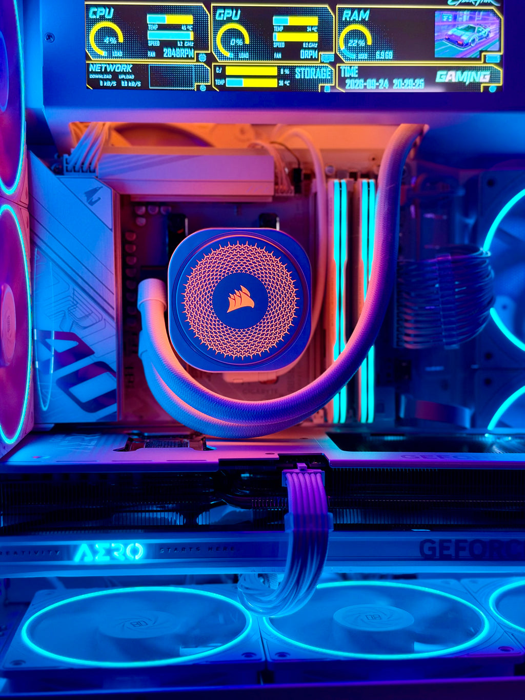 Close-up of a custom RGB PC build featuring a Corsair liquid CPU cooler with a blue and orange patterned radiator, illuminated by purple and blue LED lighting inside a glass-sided case.