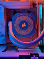 Corsair liquid CPU cooler with a blue radiator and orange logo, installed inside a white PC case with RGB lighting.