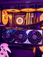 Corsair and ASRock desktop PC interior with RGB-lit fans, a large triple-fan graphics card in the foreground, and a small skull prop at the lower left.