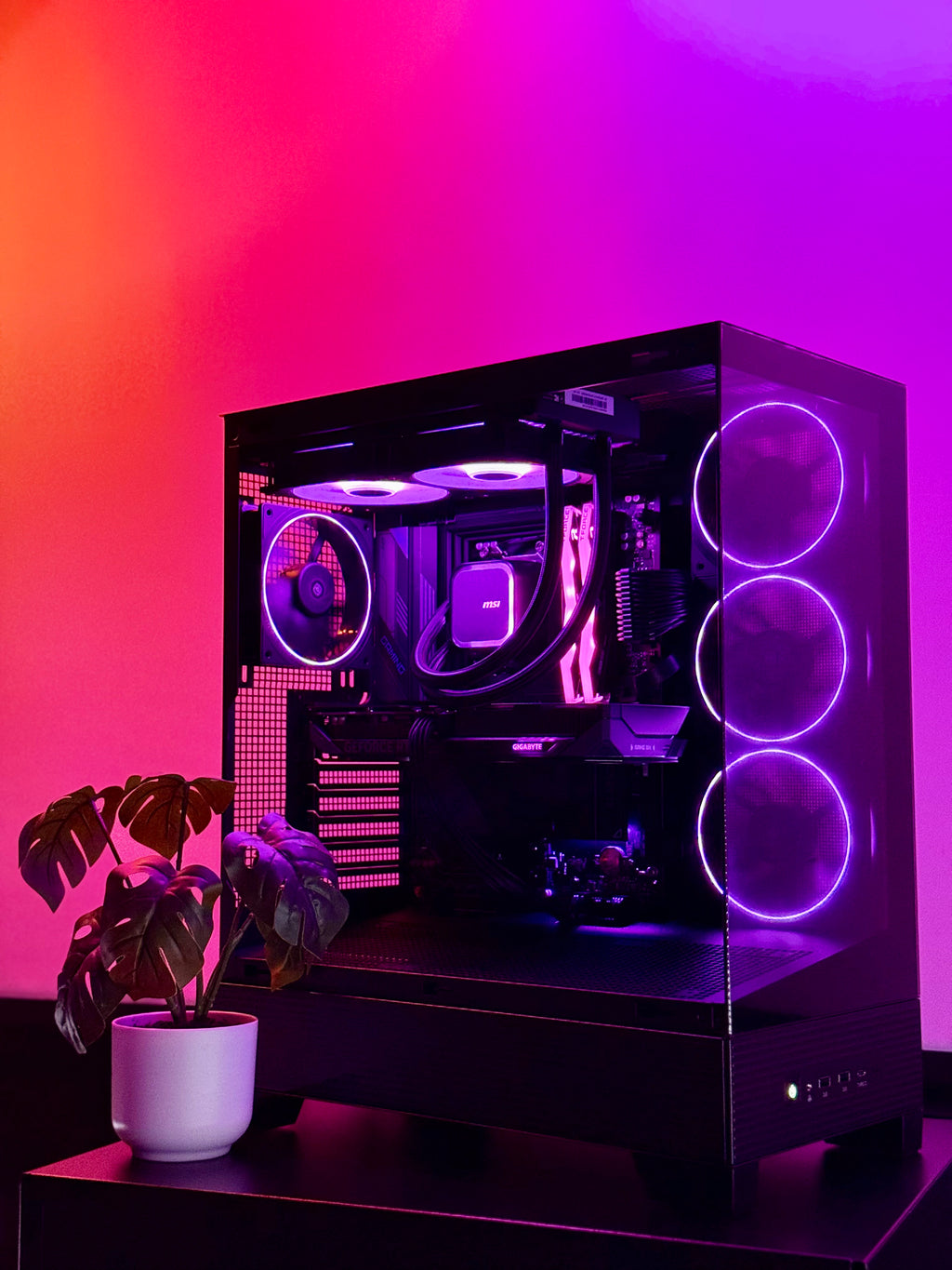 Glossy black computer case with purple lighting on a gradient pink and purple background